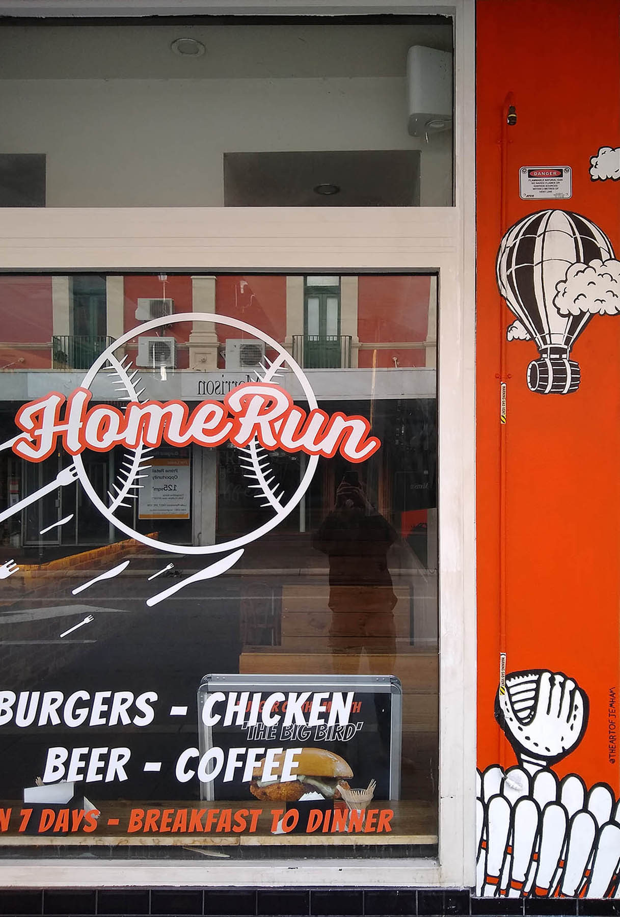 Mural of baseball burger being hit for a homerun on the front of a burger shop.